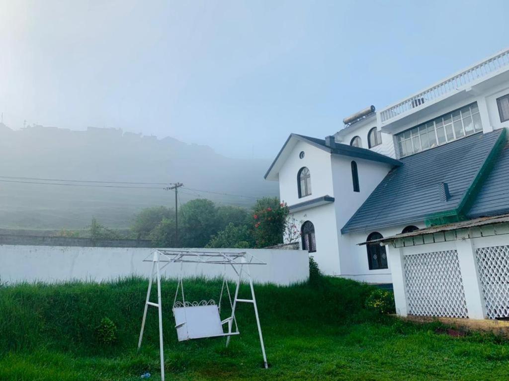 a white house with a yard with a swing at White Legacy Ooty - Families Only in Ooty