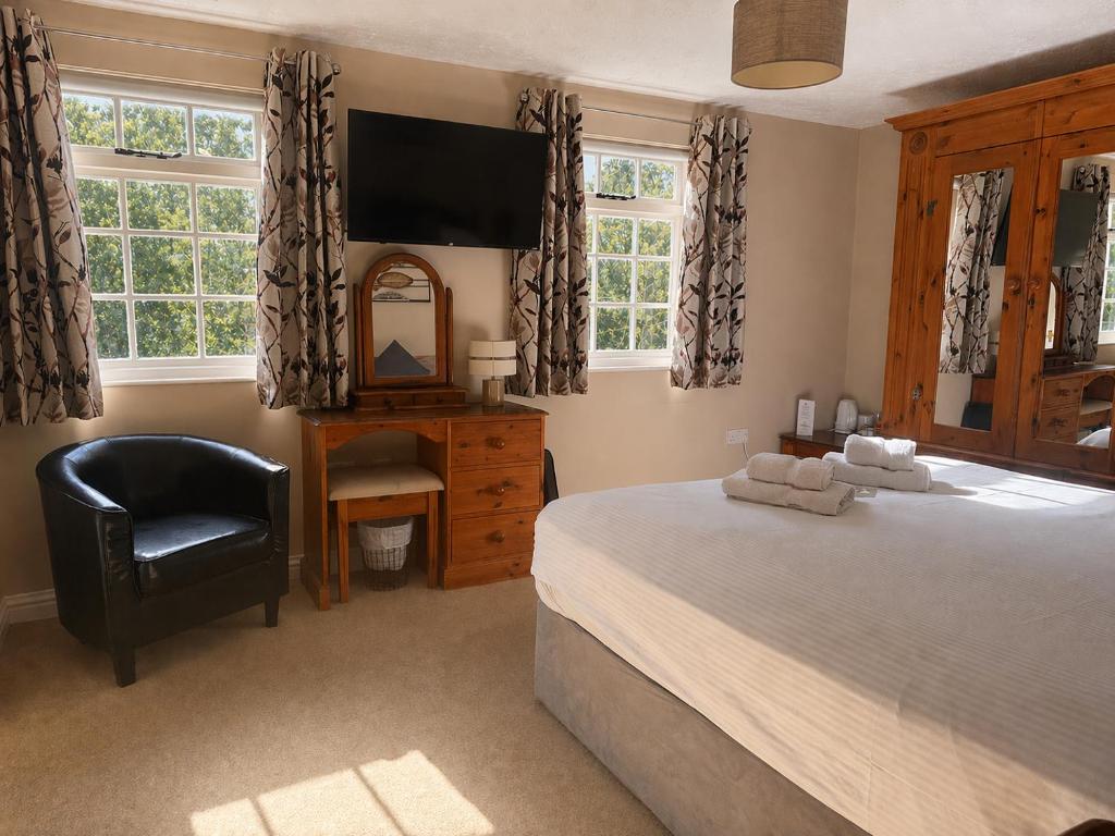 a bedroom with a bed and a chair and a mirror at The Riverside in Boscastle