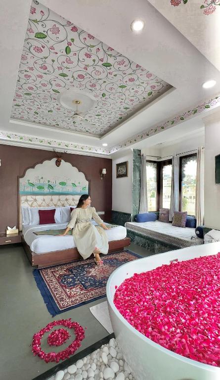ウダイプールにあるHide-In Udaipur - A Lake View Boutique hotelの花でいっぱいの部屋のベッドに座っている女性