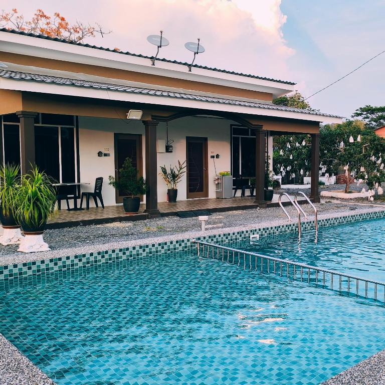 a swimming pool in front of a house at Losd Village Cottage in Kuala Perlis