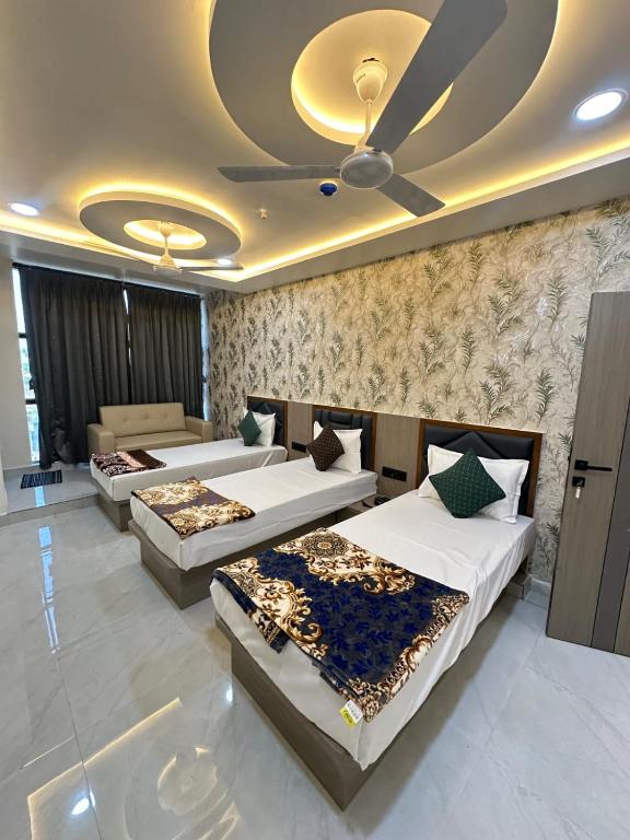 a room with three beds and a ceiling at Hotel Fortune in Ankleshwar
