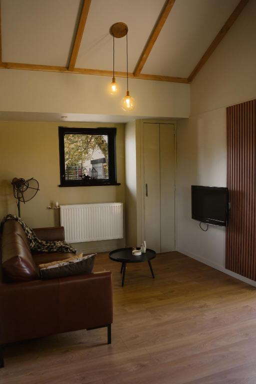 a living room with a couch and a tv at B&B de Lytse Geast in Tietjerk