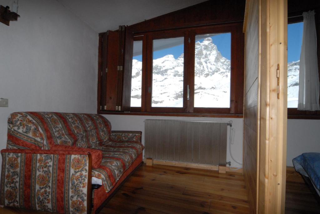 salon z kanapą i pokrytą śniegiem górą w obiekcie La Coquille Apartment w mieście Breuil-Cervinia