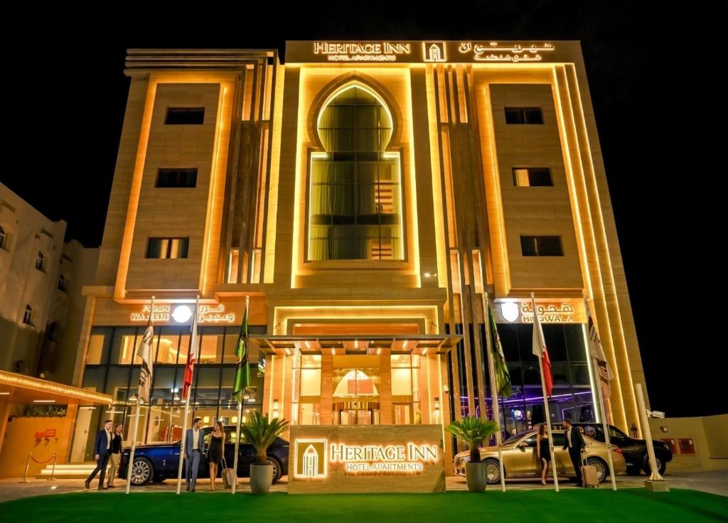 a large building with cars parked in front of it at Heritage Inn Hotel Apartments in Al Wakrah