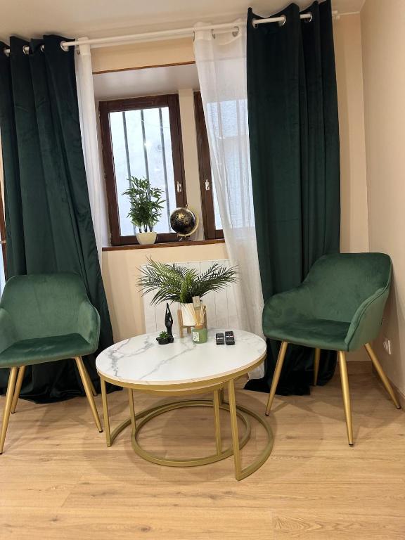 two green chairs and a table in a room at Studio design in Beaune