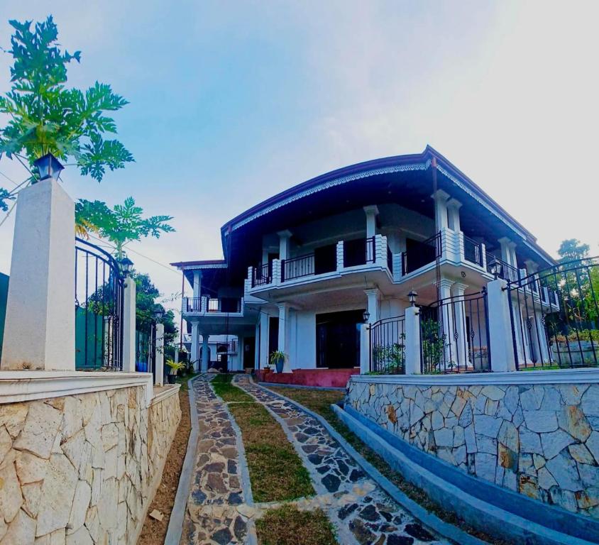 a large white house with a stone wall at Sky Palace Hikka in Hikkaduwa