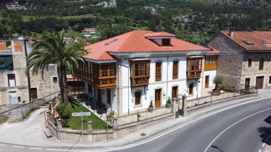 a house with a palm tree in front of a street at Loben Casona del Deva in Panes