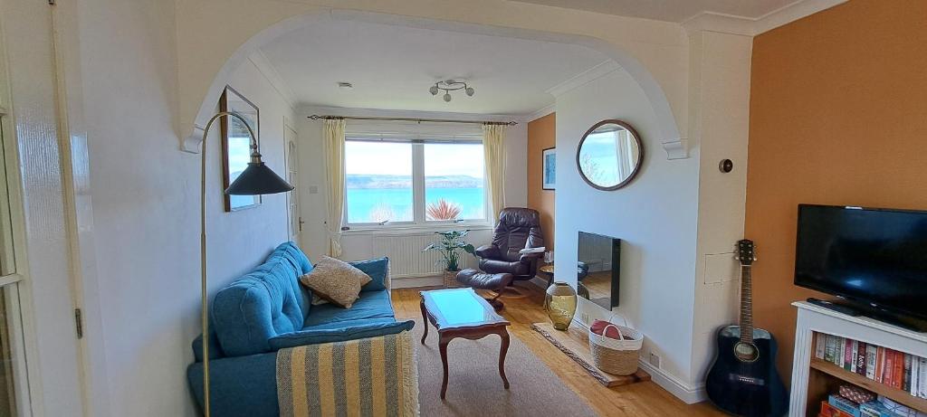 a living room with a blue couch and a tv at Seaview Cottage, Drimnin in Drimnin
