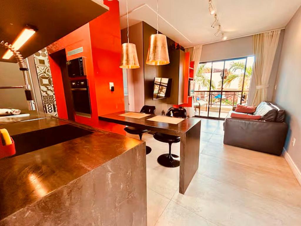 a kitchen with orange walls and a table in a room at Studio Completo a 2min da Praia e Beach Park in Aquiraz