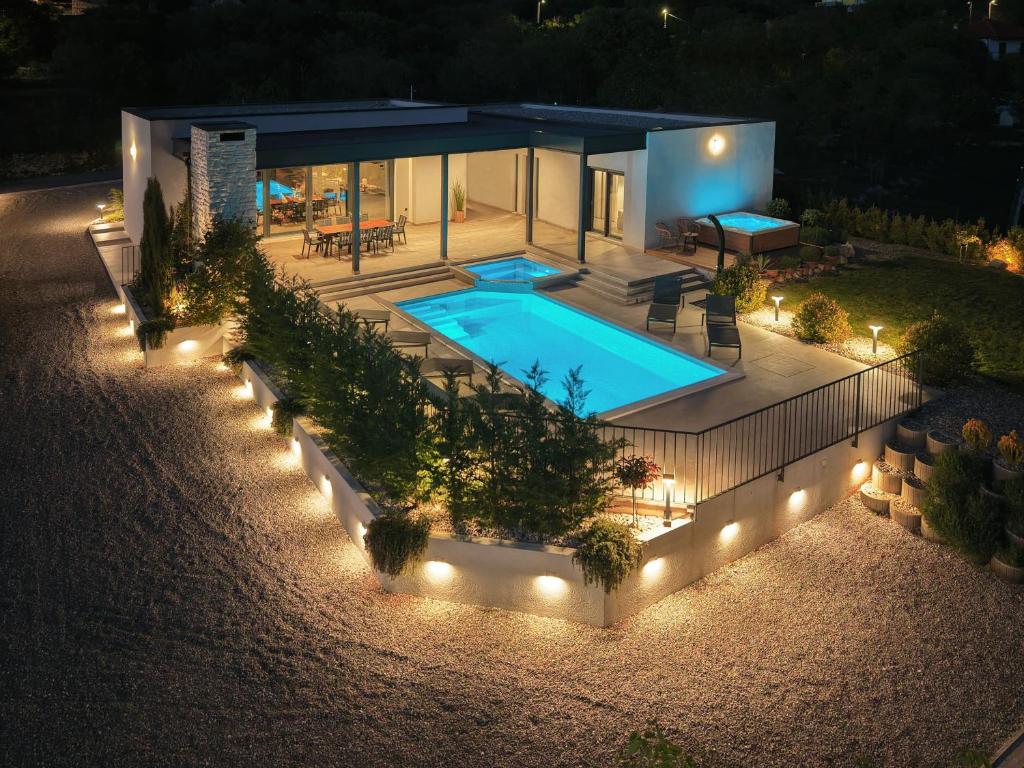 a house with a swimming pool at night with lights at Villa Harmony - Luxury Family Oasis in Nature in Lećevica