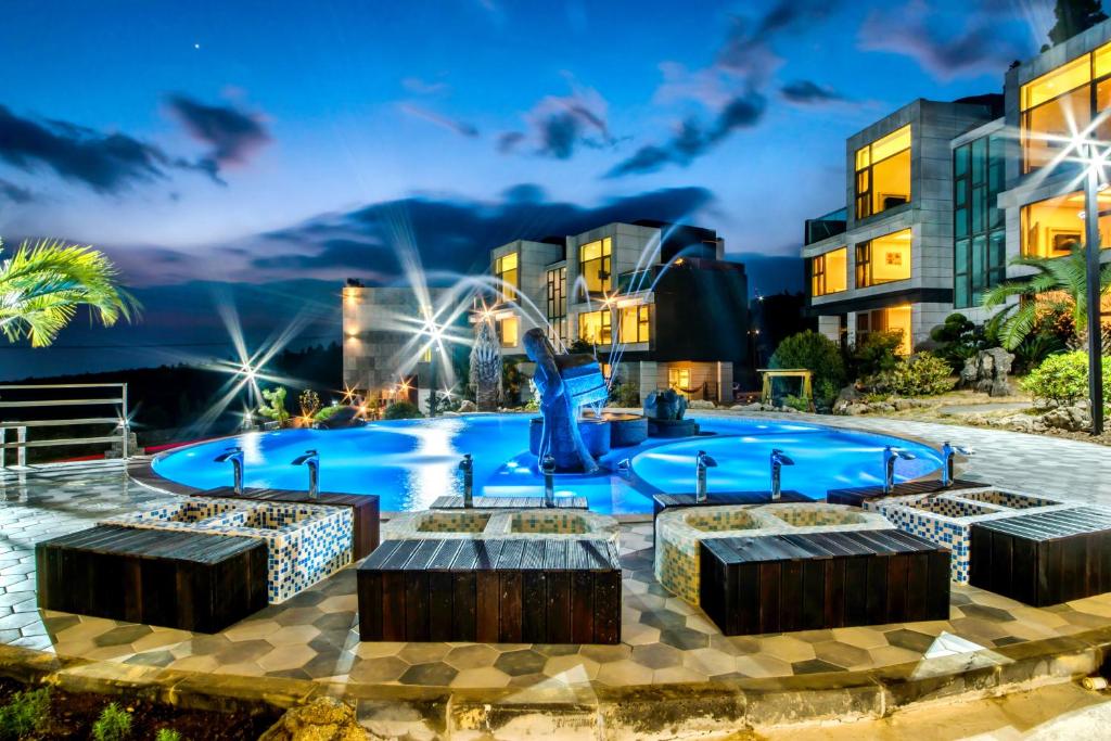 a swimming pool with four fountains in front of a building at Donnaekohill Resort in Seogwipo