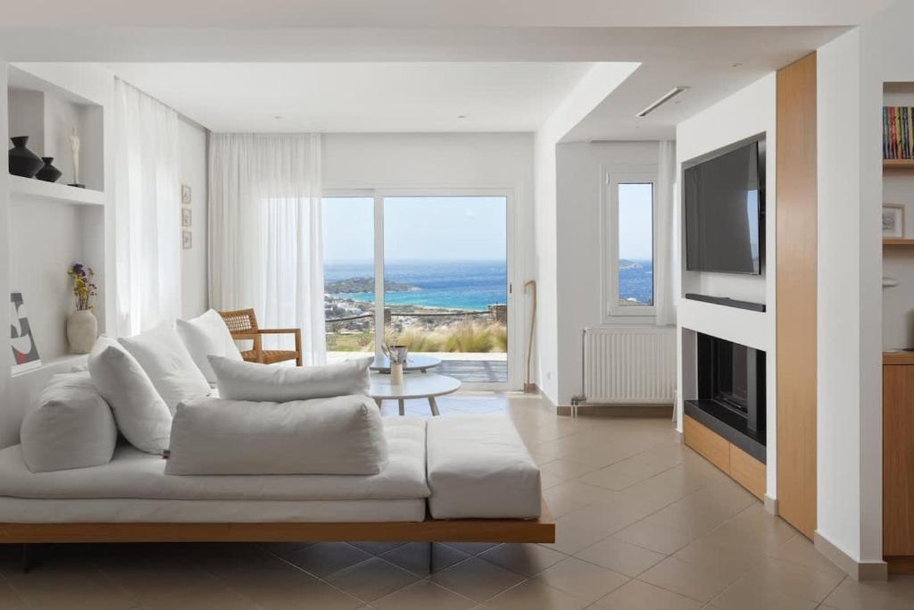 a living room with a white couch and a television at Stunning View Sarakiniko Villa in Agios Petros