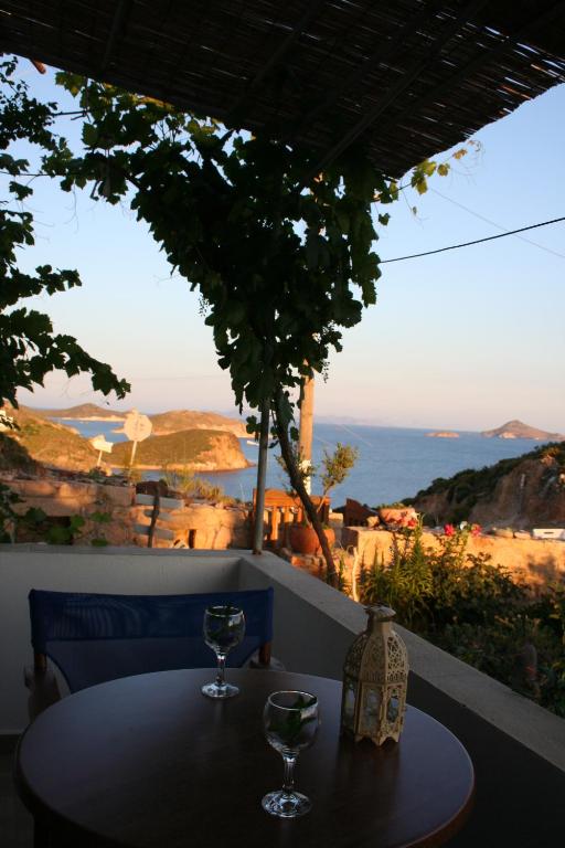 a table with two wine glasses sitting on a balcony at Chrisoula Studios in Kámbos