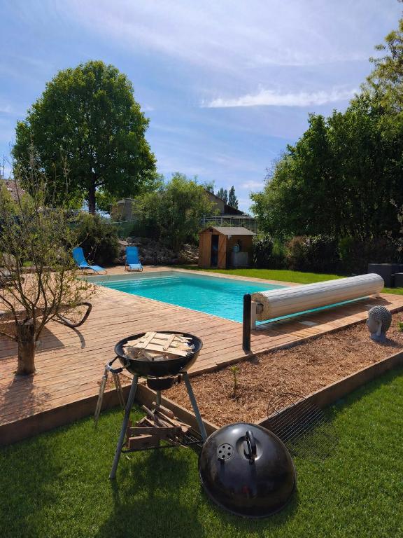 a grill and a table next to a swimming pool at Maison proche du Circuit 24h du Mans, Moto GP, Le Mans Classic in Neuville-sur-Sarthe