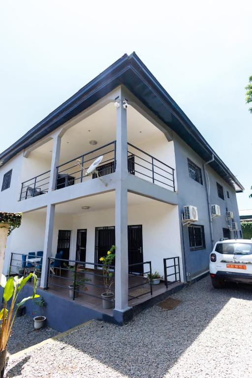 a white house with a car parked in front of it at Duplex MNE in Douala