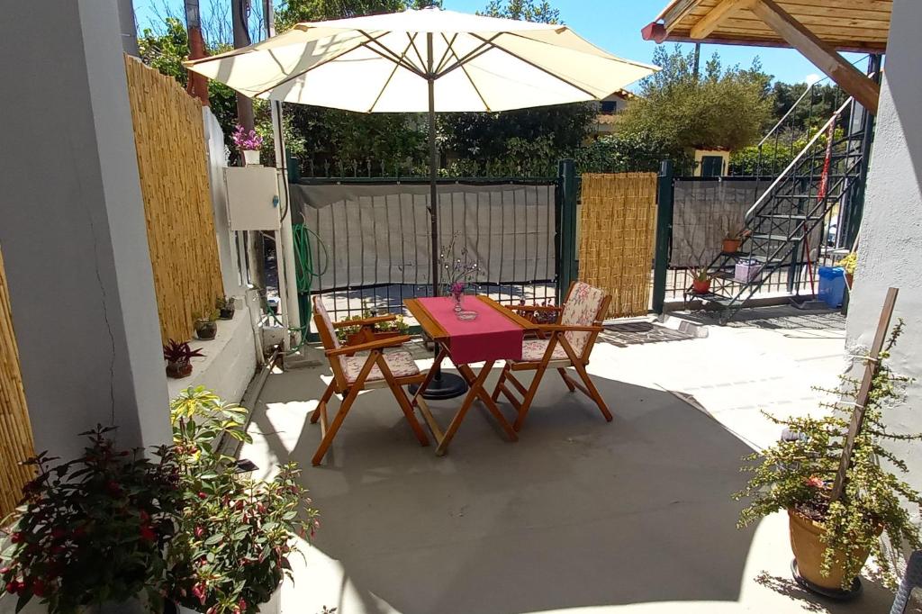 a table and chairs with an umbrella on a patio at Elizas house in Nea Makri