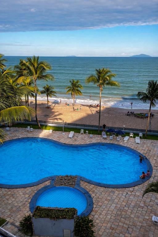 a large blue swimming pool next to a beach at Apto pe na areia 3 dorm ar cond in Caraguatatuba