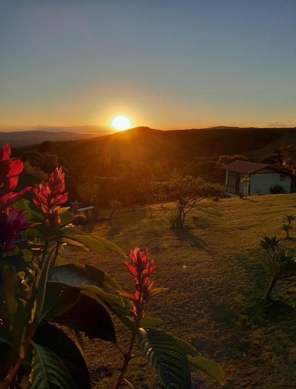 a sunset over a field with a house in the background at Pousada Canto da Lua - Charme, intimismo e uma linda vista para o Pôr-do-Sol -Wi-Fi in Carrancas
