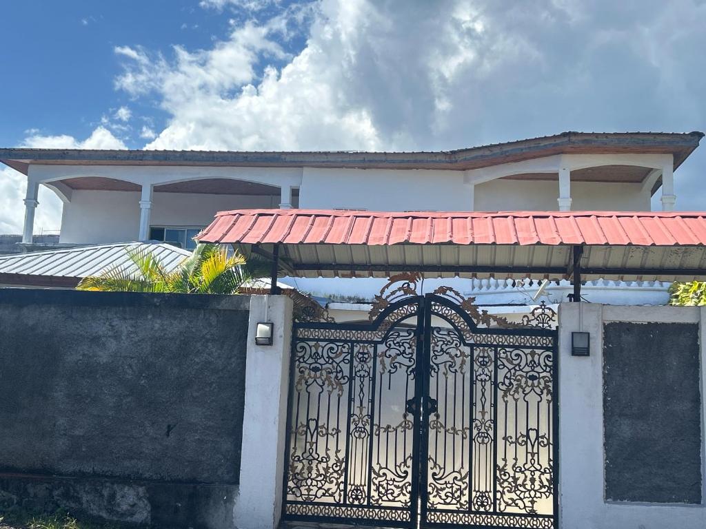 a white house with a gate with a red roof at Amalis in Moroni