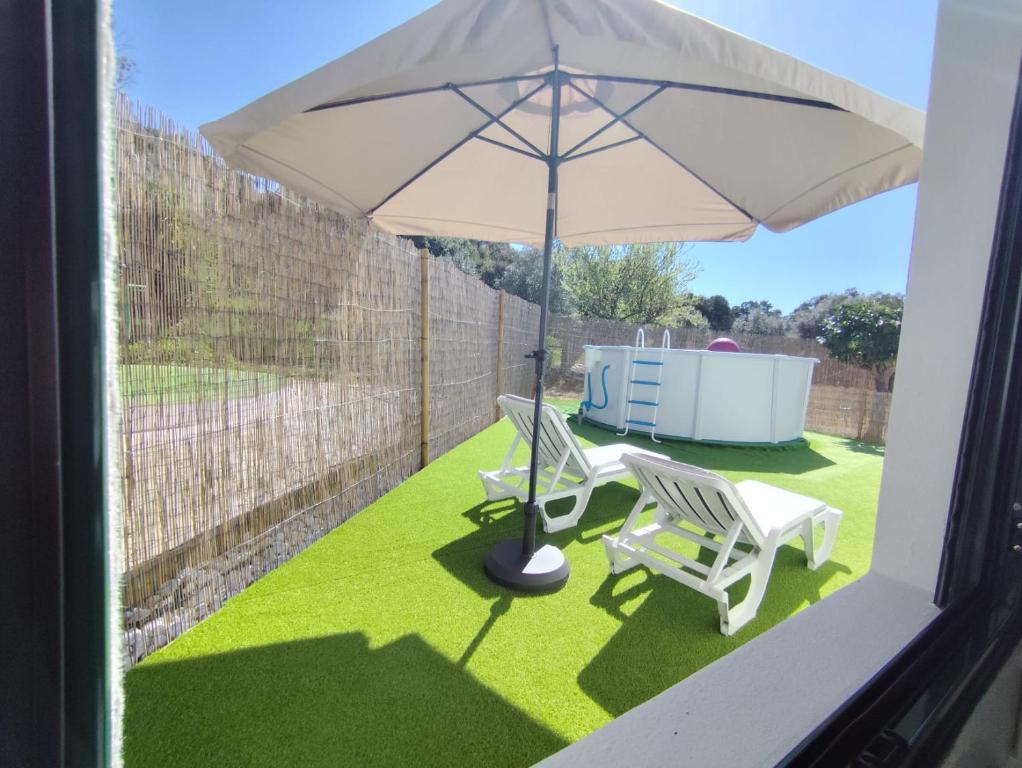 a patio with two chairs and an umbrella at Toca da Raposa in Estremoz