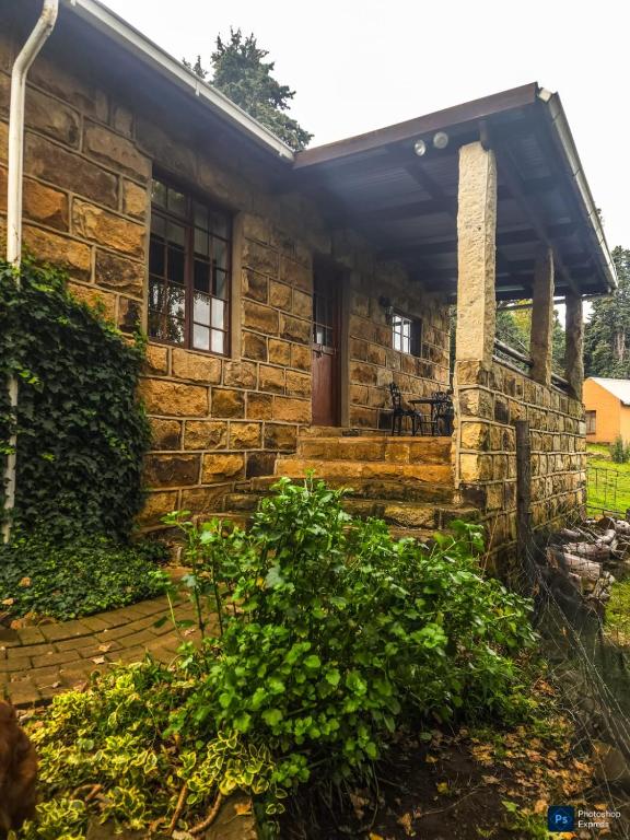 a stone house with a roof and a porch at The GingerPig Inn in Die Ark