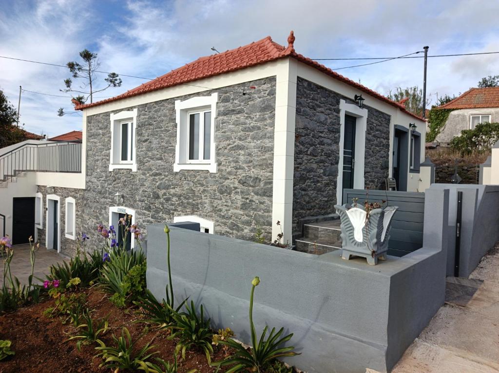 a stone house with a fence in front of it at Adelaide's Cottage in Ponta do Pargo