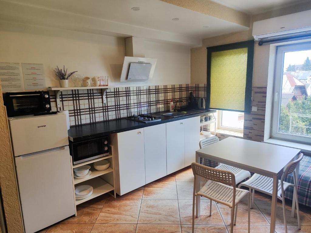 a kitchen with white cabinets and a table and a window at Comfort Akacija Apartments in Vilnius