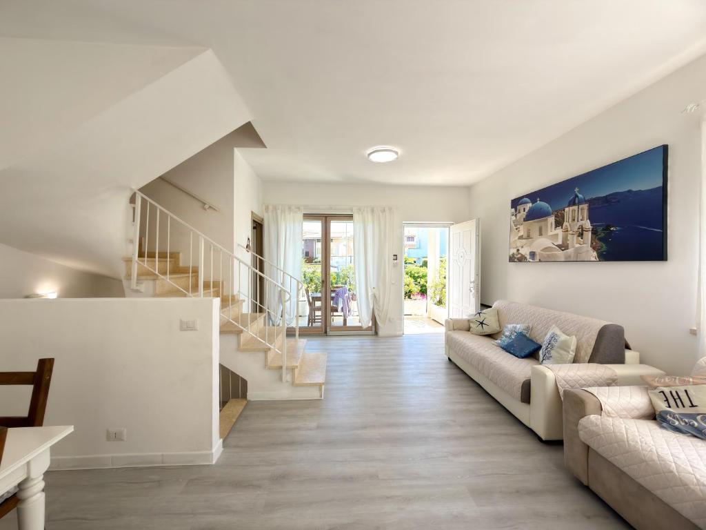 a white living room with a couch and stairs at Nice villa only 100m from the beach in Fregene