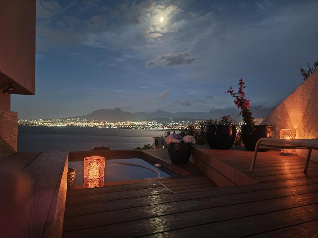 a hot tub on a deck with a view of the water at Villa Solace in Gordonʼs Bay
