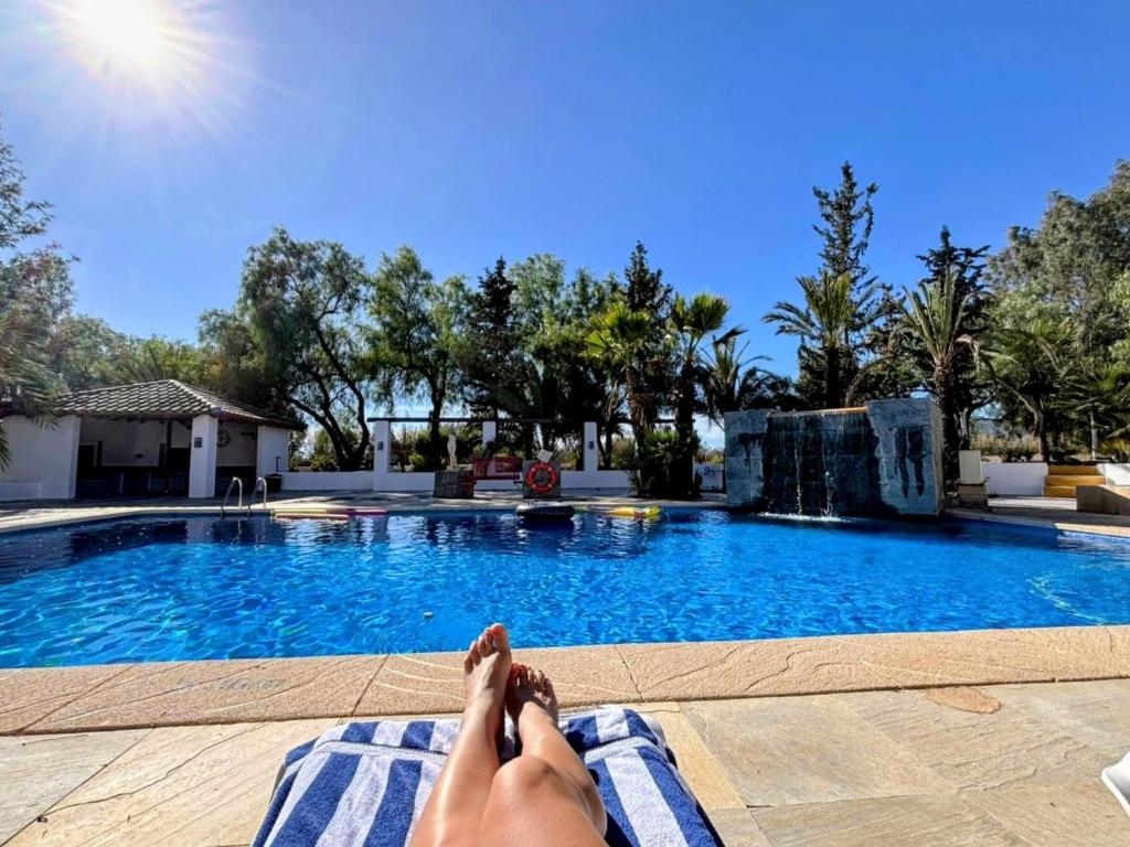 a person laying on a towel next to a swimming pool at Rezen Villas in Lorca