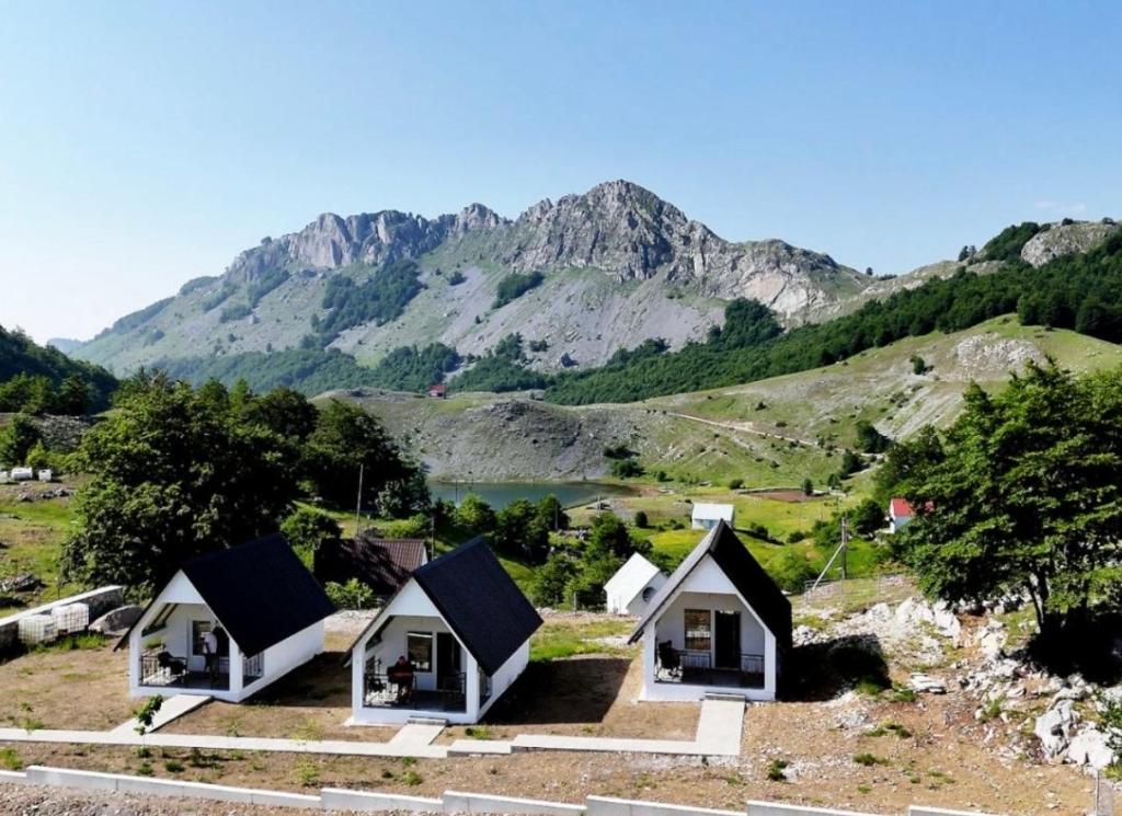 Eine Gruppe von Ferienhäusern mit einem Berg im Hintergrund in der Unterkunft Vikendice Ivanović in Prisoja