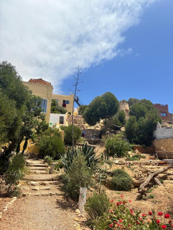 a garden with a house and trees and flowers at Easy Going Imsouane in Imsouane