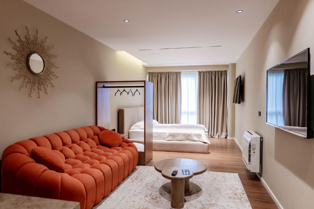 a living room with a red couch and a bed at Agate Hotel Tirana in Tirana