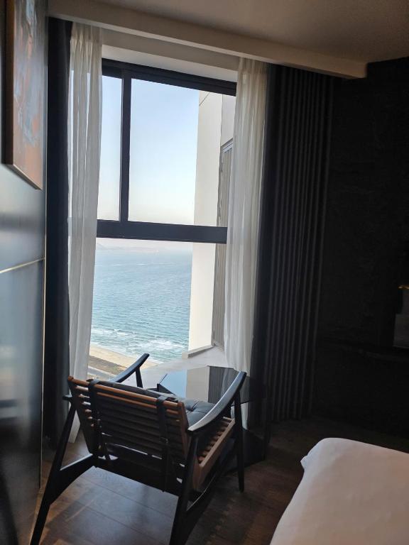 a bedroom with a desk and a window with the ocean at Mandala Chambay Mũi Né - TAQ in Mui Ne