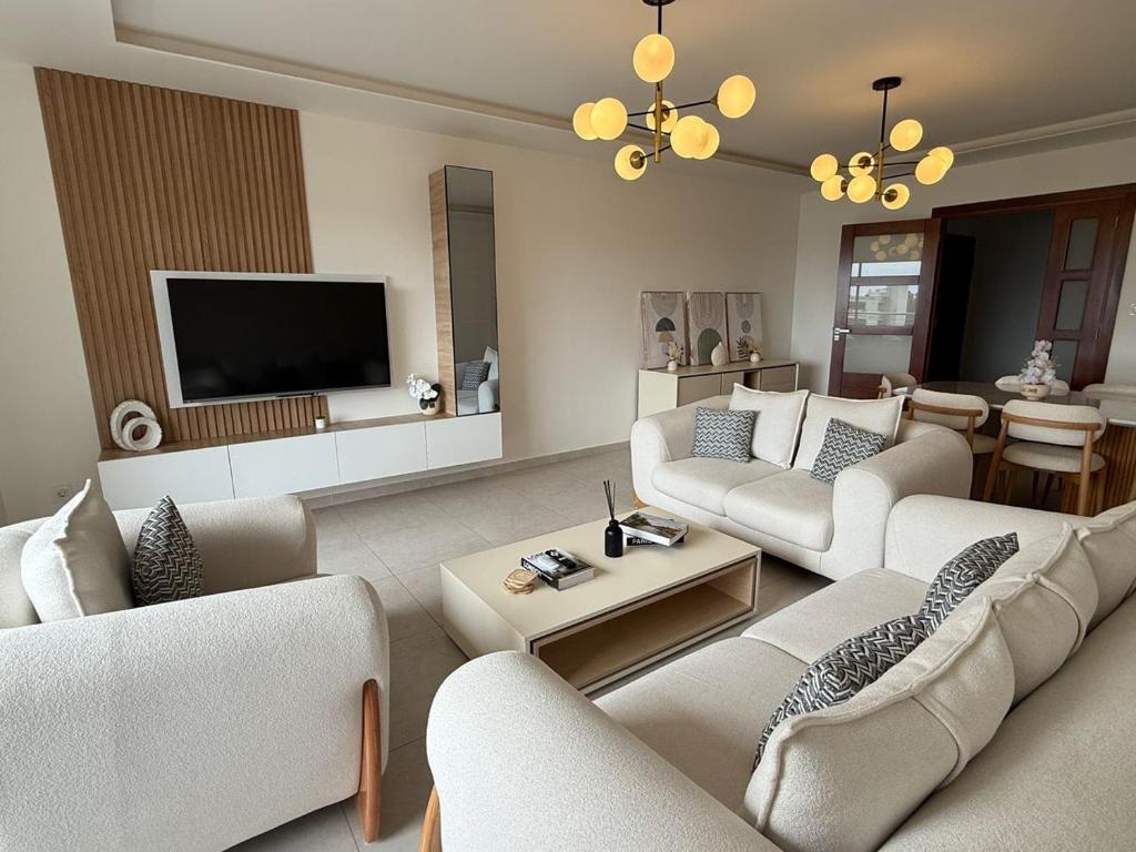 a living room with white furniture and a flat screen tv at Sublime appartement F4 a draria in Alger