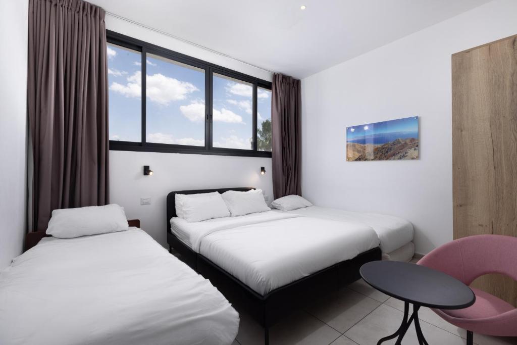 two beds in a room with a table and a chair at Razin 37 in Eilat