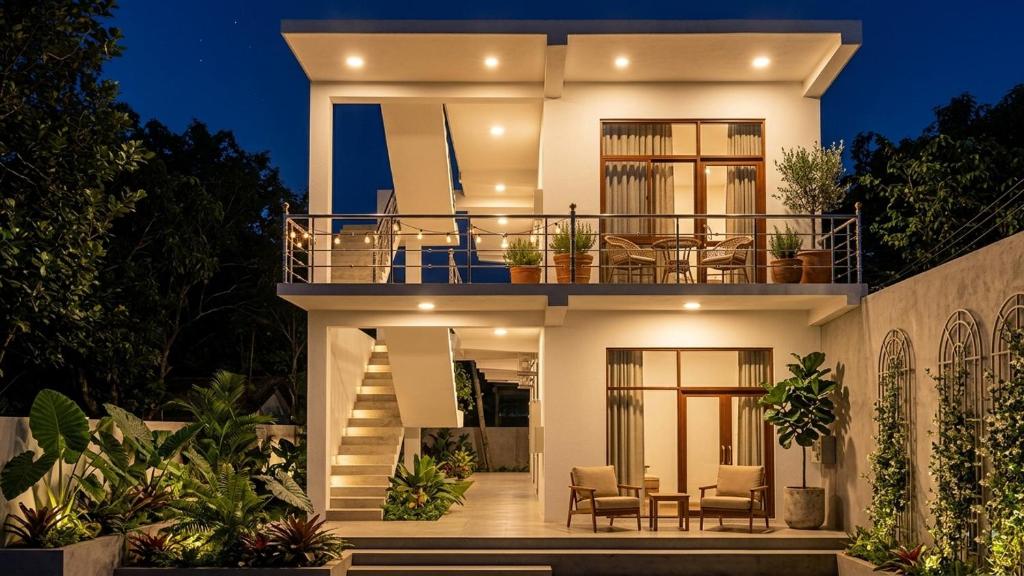 a large white house with a balcony at night at Butterfly Homestead Hotel in Udawalawe
