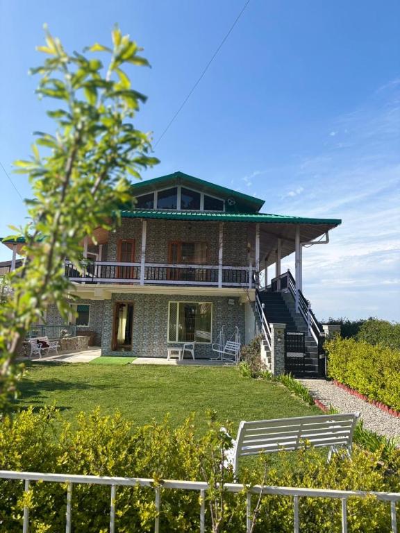 a large house with two benches in front of it at Highfield Villa in Kanatal