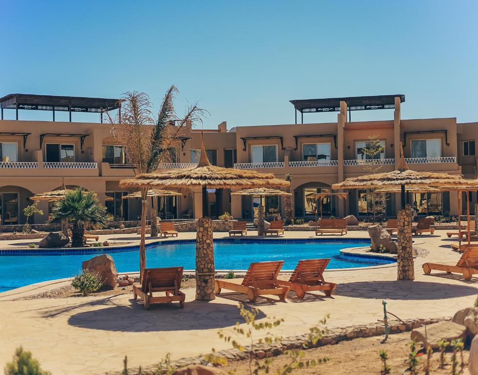 a resort with a swimming pool with chairs and umbrellas at Green studio in Dahab in Dahab