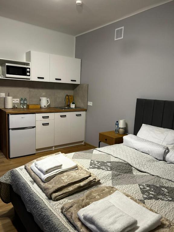 a room with two beds and a kitchen with white cabinets at Hello Tu Modlin in Zakroczym