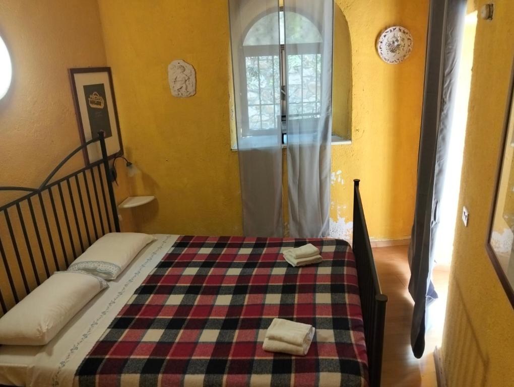 a bedroom with a bed with a checkered blanket and a window at Appartamento Gelsomino in Montale