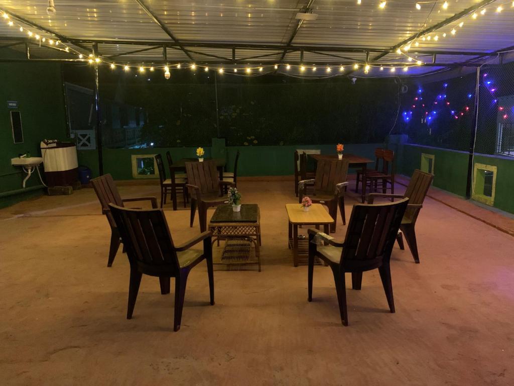 a dining room with tables and chairs and lights at Pinetree Stay in Kodaikānāl
