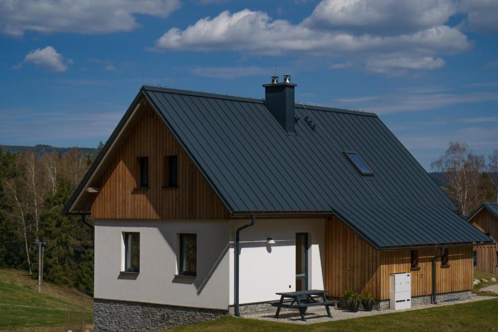 a barn with a black roof and a white house at Chata Špička in Smržovka
