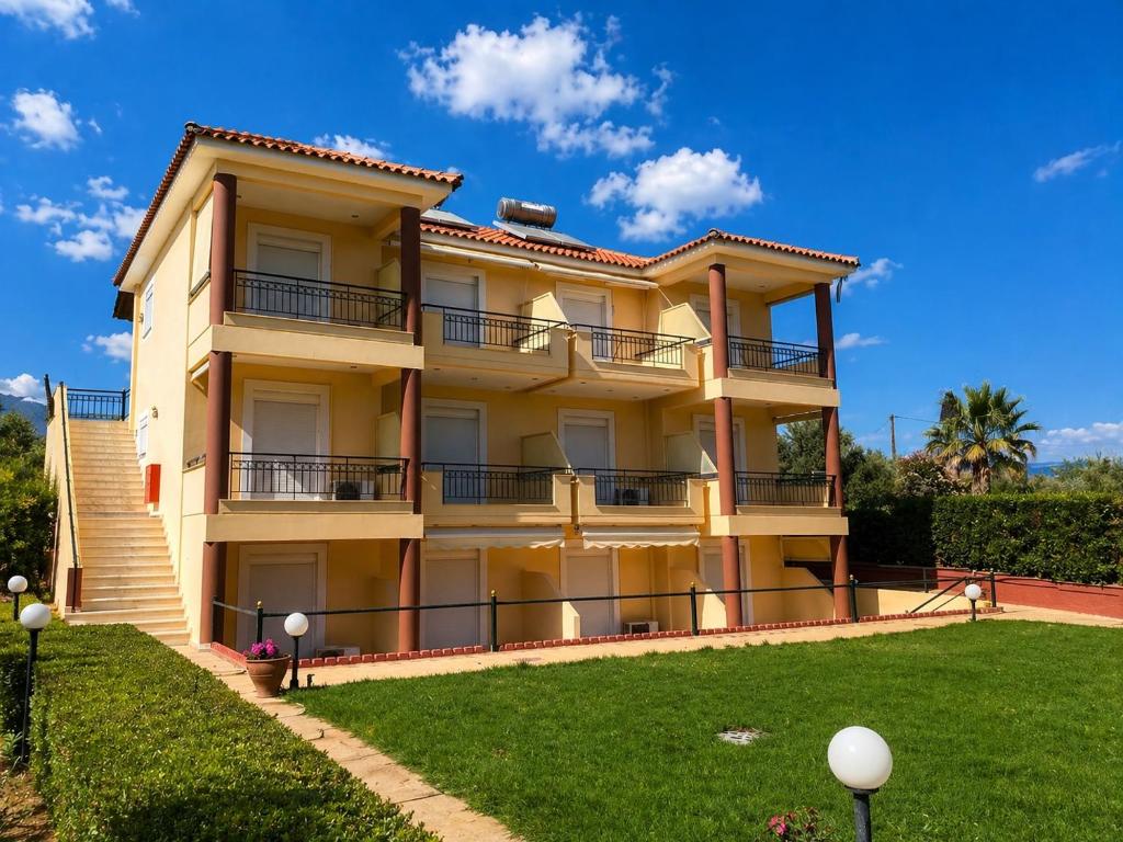 a large apartment building with a lawn in front of it at Τηλεμαχος Apartments in Loutra Edipsou