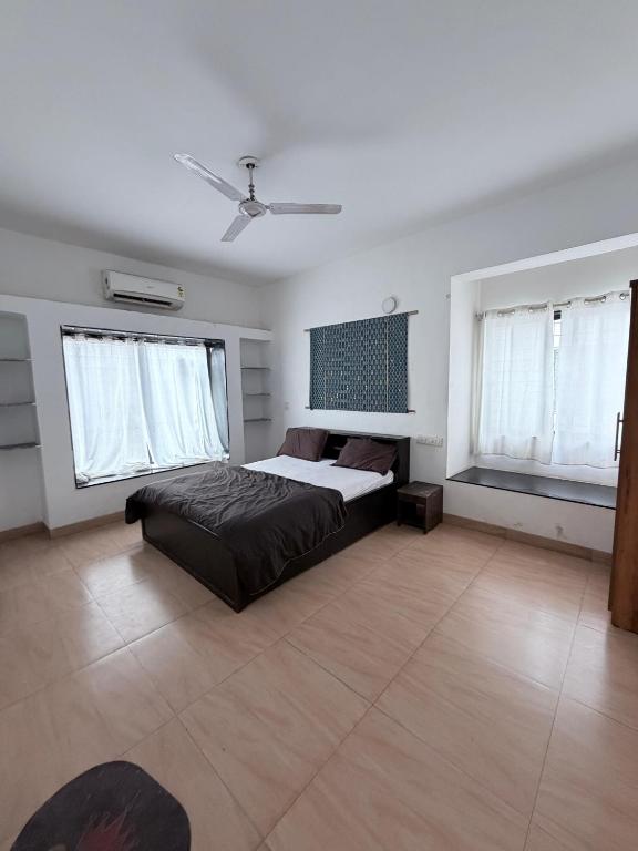 a bedroom with a bed and two windows at Hidden Hearts Cottage in Lonavala