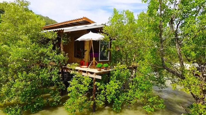 een klein huis met een paraplu in de bomen bij Deep House Sea View in Koh Lanta