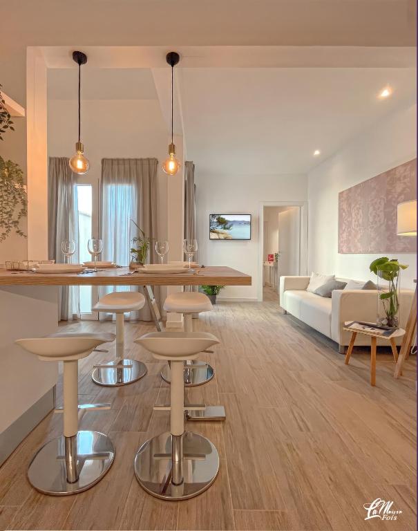 a kitchen and living room with a table and stools at La Maison Fois - Appartamento Quartucciu in Quartucciu