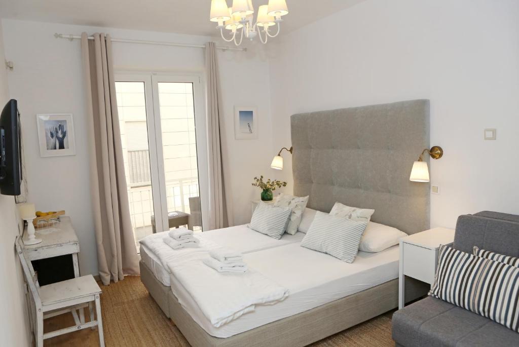 a bedroom with a large white bed and a chair at Hotel Delfin in Zadar