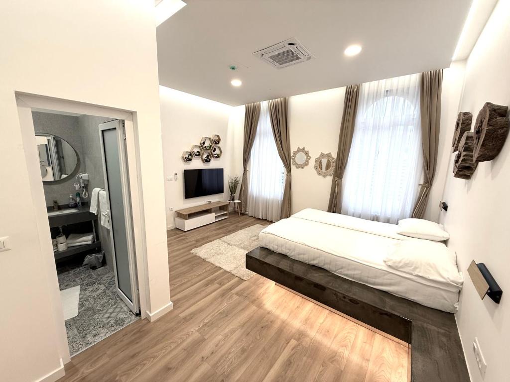a white bedroom with a bed and a television at Biosphere Lux Apartments in Sarajevo