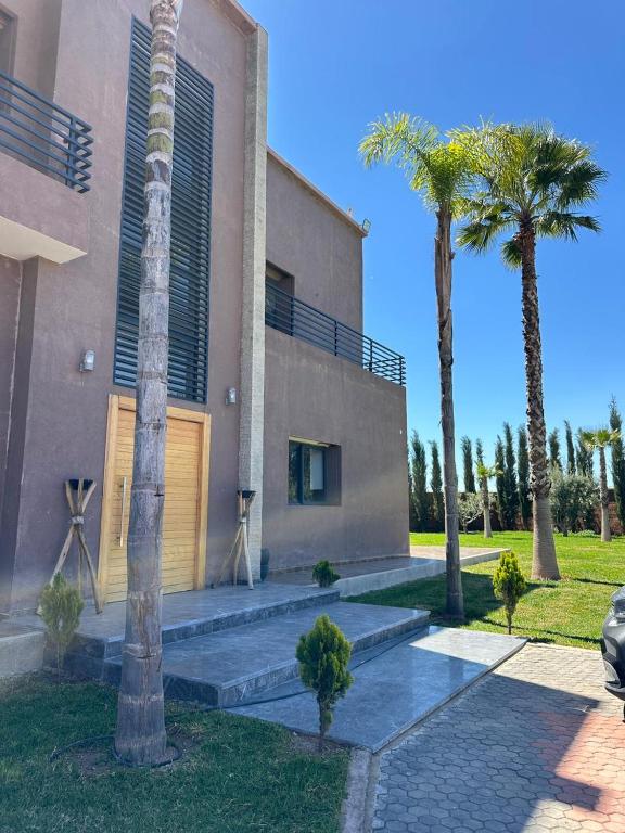 a building with palm trees in front of it at Villa Dream el filali in Sraghna